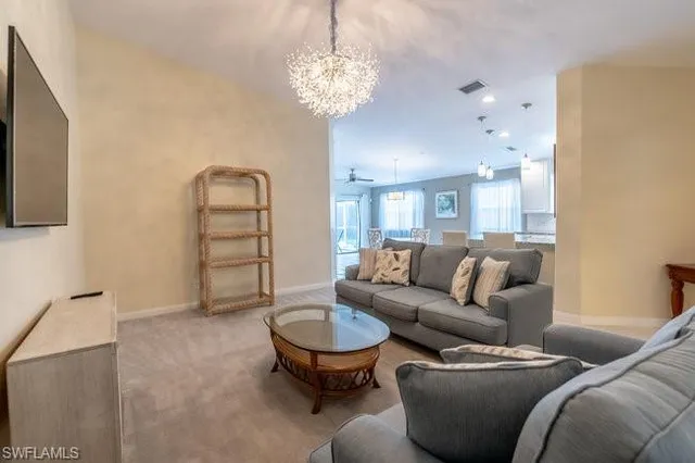 a living room with furniture a chandelier and a flat screen tv