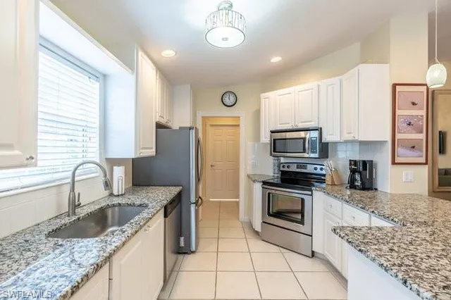 a kitchen with stainless steel appliances granite countertop a sink a stove a refrigerator cabinets and a dining table