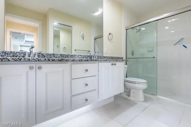 a bathroom with a granite countertop sink a toilet and a mirror
