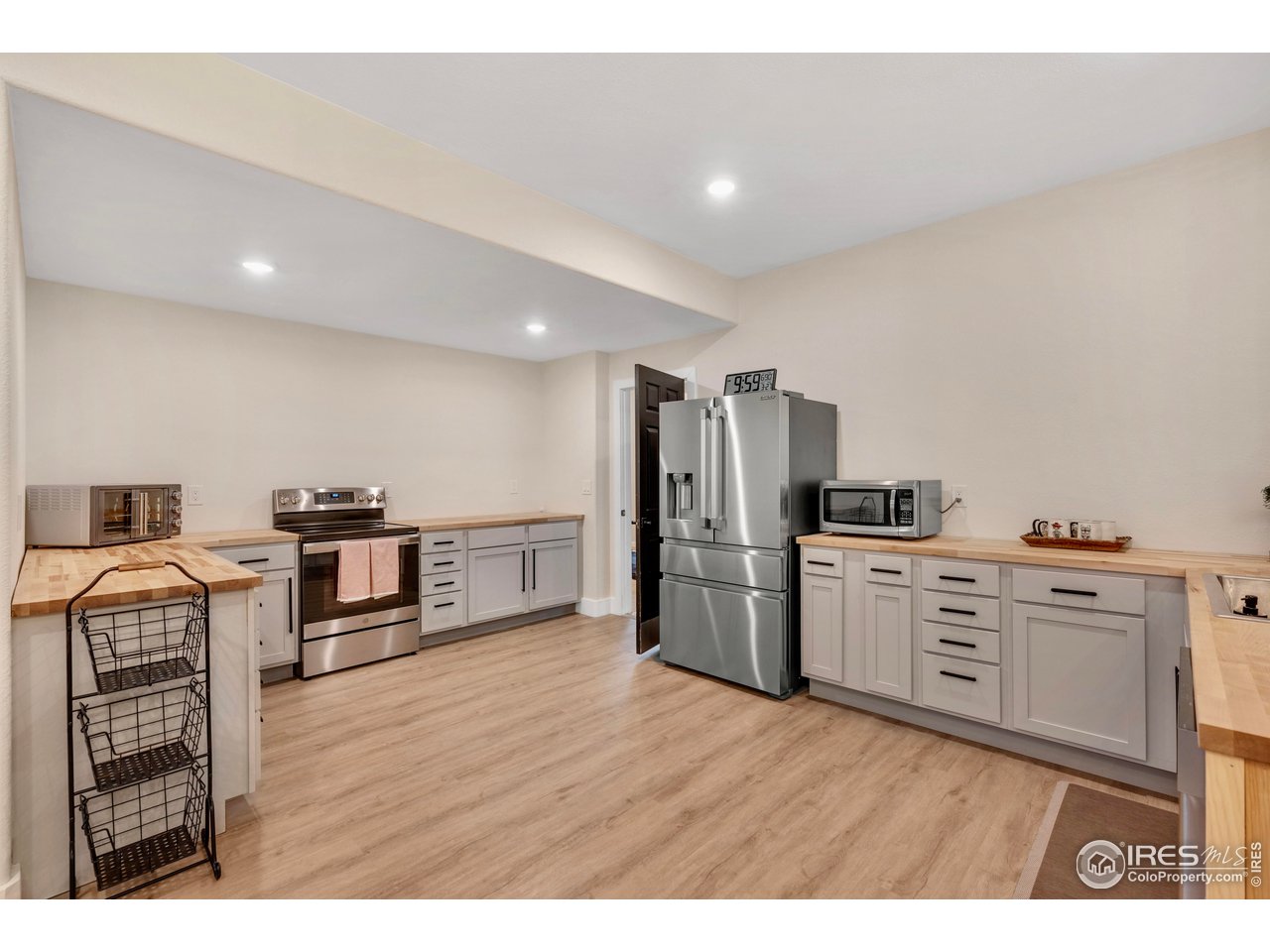 3058 West 111th Drive Westminster, CO 80031 - Photo 23 of 39 a kitchen with stainless steel appliances kitchen island wooden floors and white cabinets