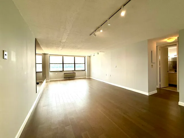 an empty room with wooden floor and windows