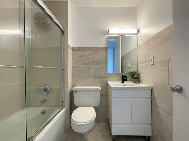 a bathroom with a bathtub shower sink mirror and toilet