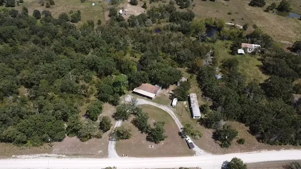 an aerial view of a house with a yard and trees