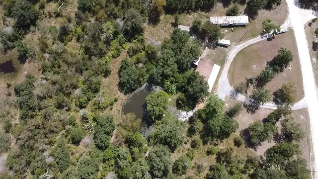 an aerial view of residential house with outdoor space and trees all around