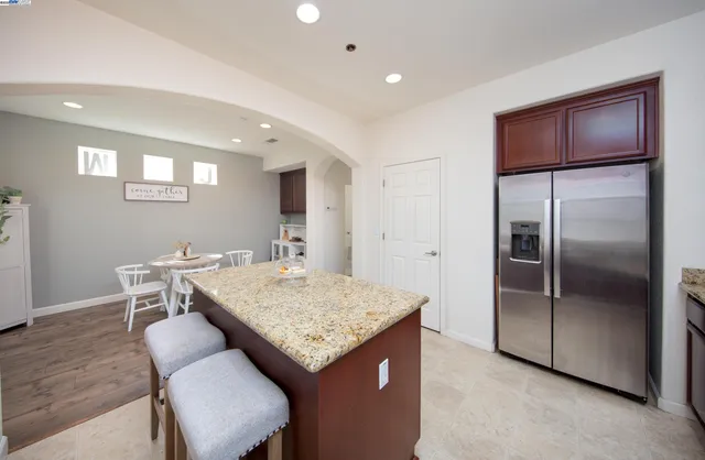a kitchen with stainless steel appliances granite countertop refrigerator sink dining table and chairs
