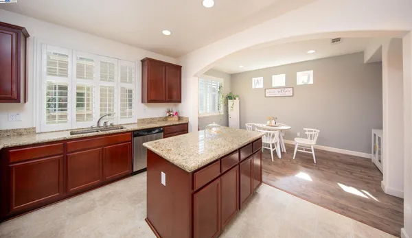 a kitchen with stainless steel appliances granite countertop a sink a stove a dining table and chairs