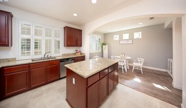 a kitchen with stainless steel appliances granite countertop a sink a stove a dining table and chairs