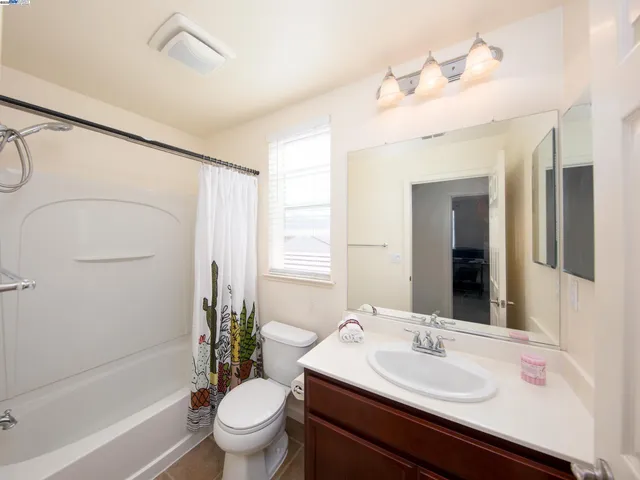 a bathroom with a sink a toilet a mirror a vanity a bathtub and shower