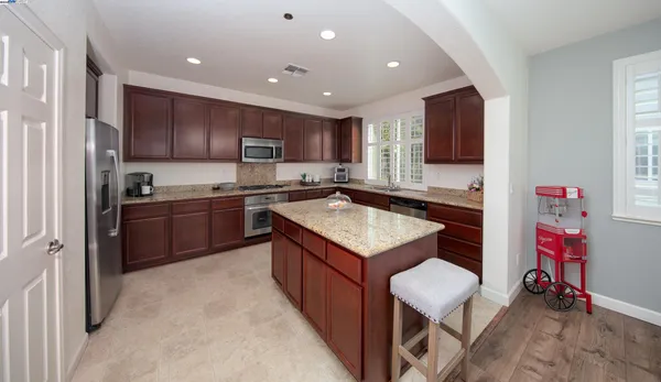 a kitchen with kitchen island granite countertop wooden cabinets a sink and a stove