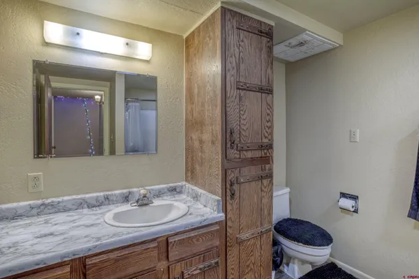 a bathroom with a granite countertop sink a toilet a mirror and shower