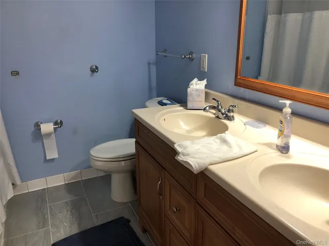 a bathroom with a granite countertop sink a toilet and a mirror