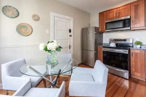 a kitchen with stainless steel appliances granite countertop a stove top oven a refrigerator with a dining table and chairs
