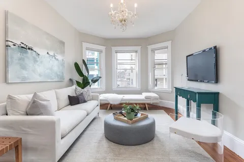 a living room with furniture a flat screen tv and a large window
