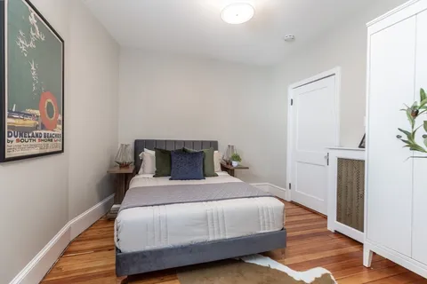 a bedroom with a bed and wooden floor