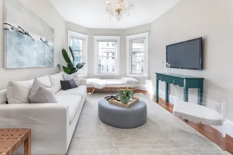 a living room with furniture a flat screen tv and a large window