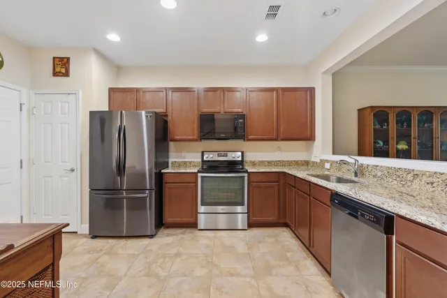 a kitchen with stainless steel appliances granite countertop a refrigerator and a stove top oven