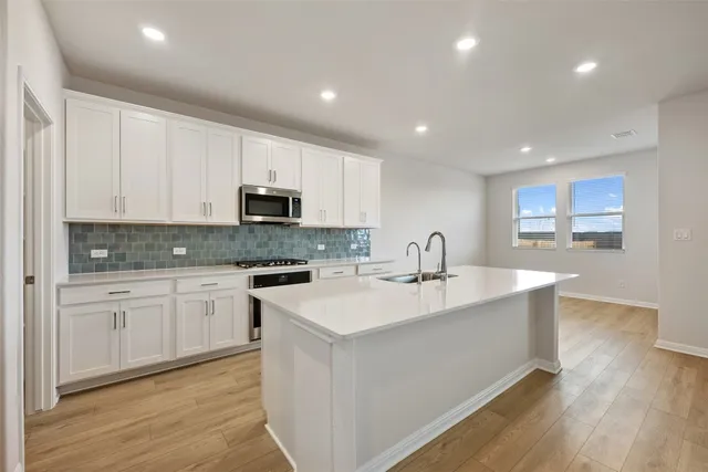 a kitchen with granite countertop white cabinets and stainless steel appliances