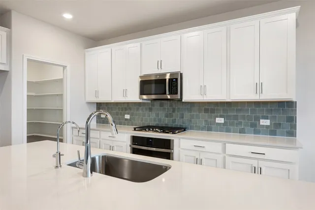 a kitchen with stainless steel appliances a stove a sink a microwave a refrigerator and cabinets