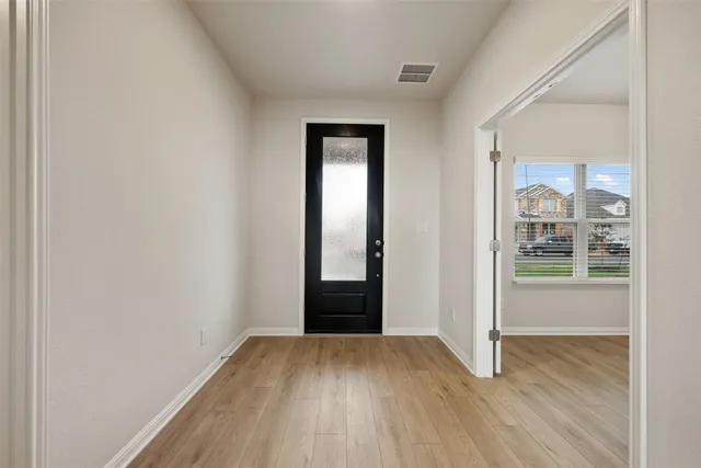 a view of an empty room with wooden floor and a window