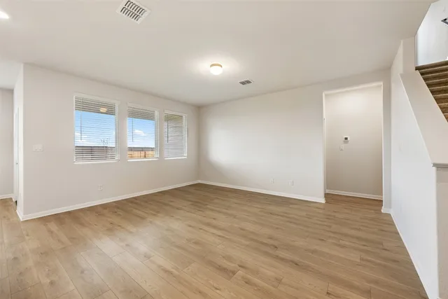 a large kitchen with stainless steel appliances granite countertop a stove a sink and white cabinets with wooden floor