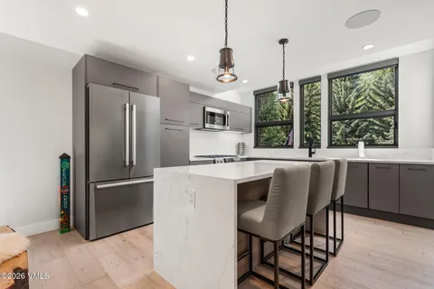 a kitchen with stainless steel appliances granite countertop a refrigerator a stove a sink a dining table and chairs with wooden floor