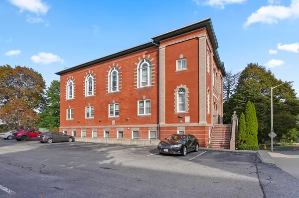 a view of building with cars parked in front of it