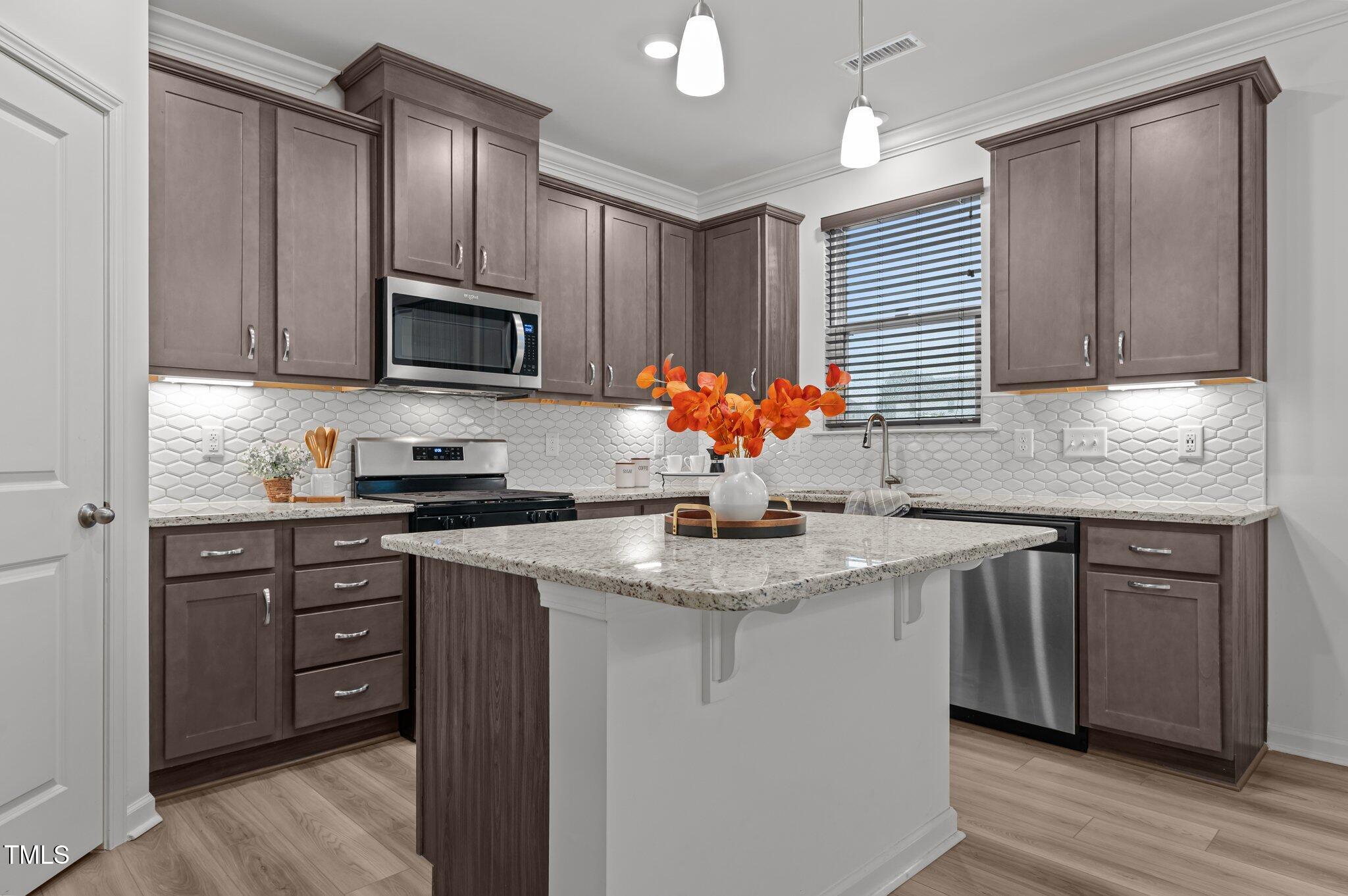 a kitchen with stainless steel appliances granite countertop a sink stove microwave and refrigerator