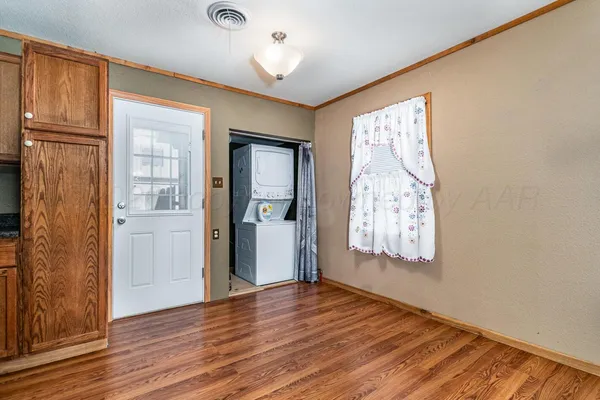 a kitchen with granite countertop a refrigerator a sink dishwasher a stove and white cabinets with wooden floor