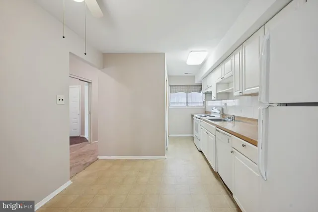 a large white kitchen with granite countertop a sink and white cabinets