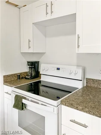 a kitchen with granite countertop white cabinets and white appliances
