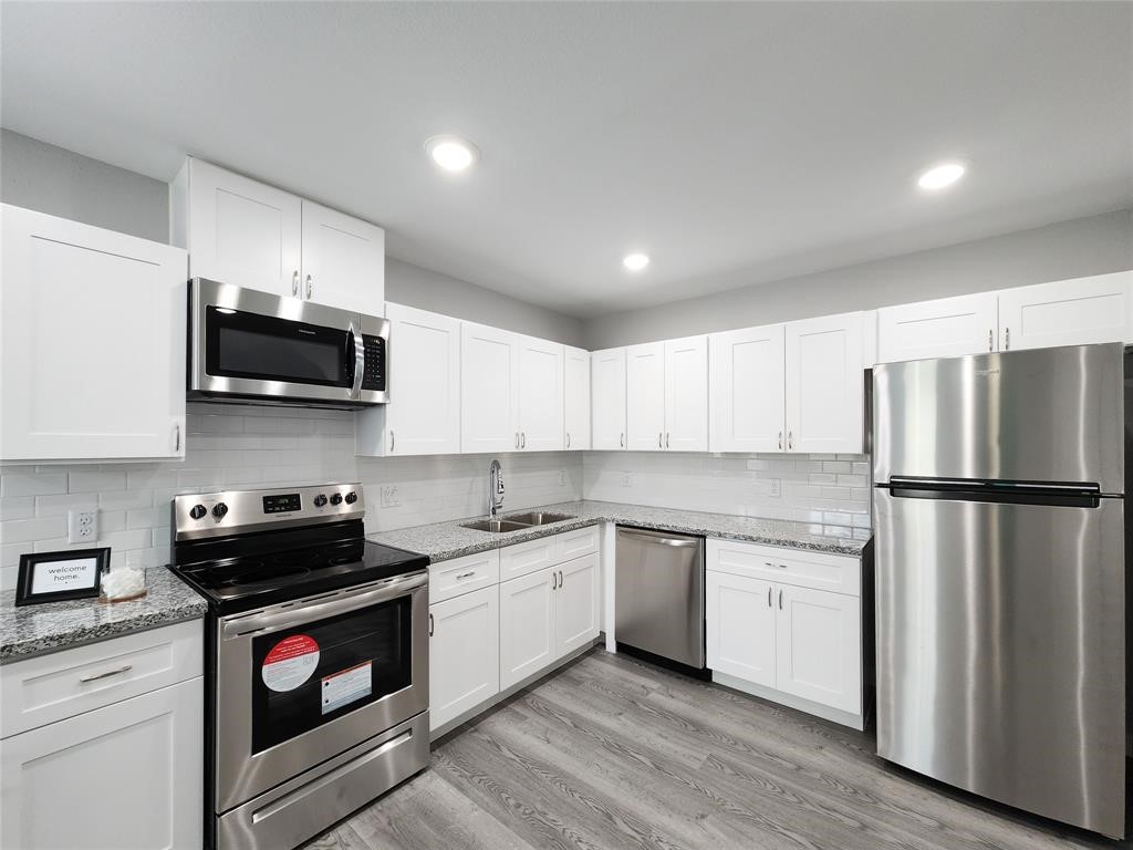 7735 Orebo Street, Unit B Houston, TX 77088 - Photo 3 of 14 a kitchen with stainless steel appliances a white stove top oven a sink and dishwasher a refrigerator with wooden floor