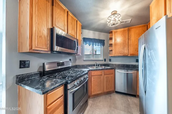 a kitchen with stainless steel appliances granite countertop a stove a sink and a microwave