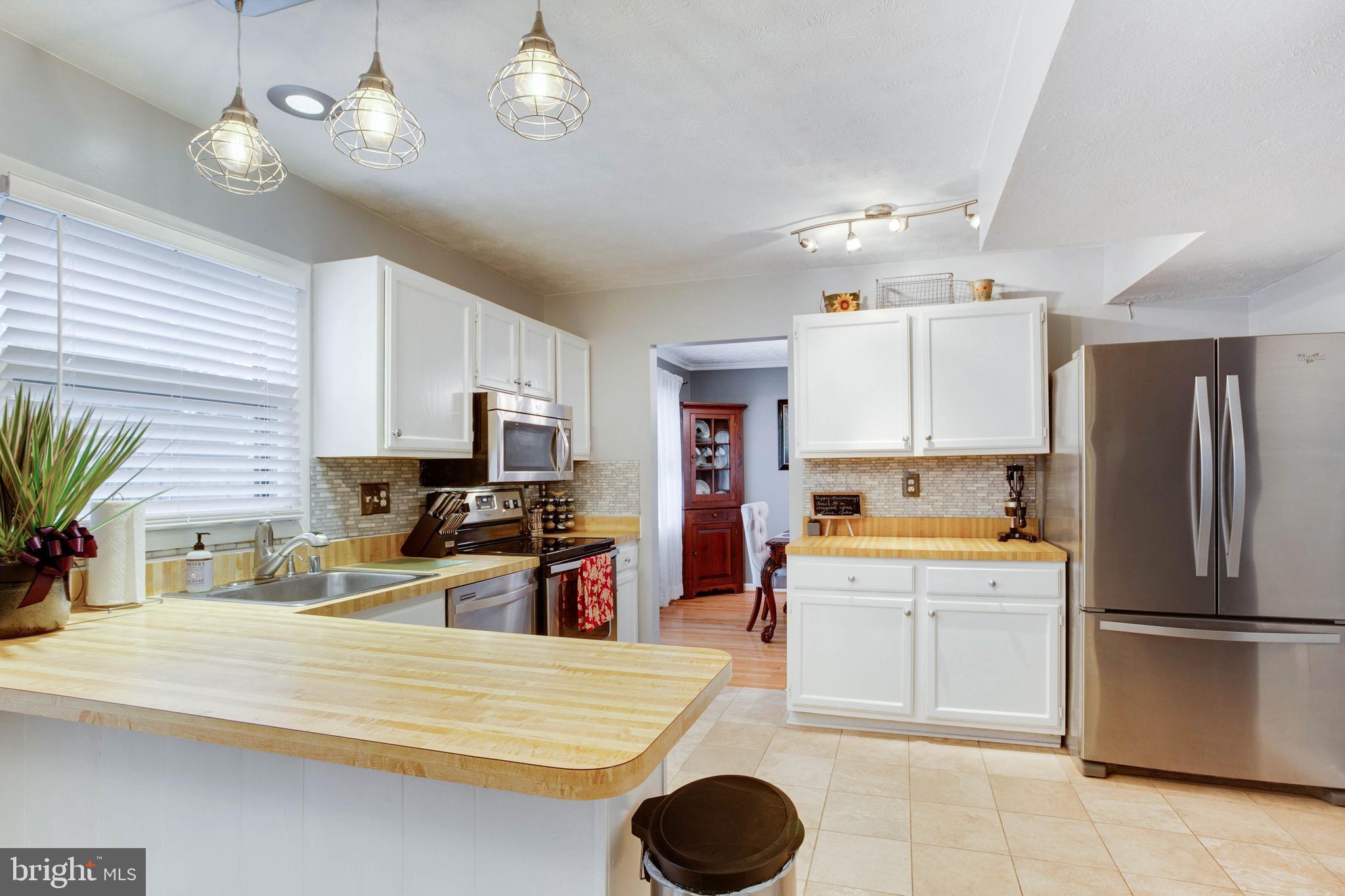 1872 Montreal Road Severn, MD 21144 - Photo 12 of 36 a kitchen with a refrigerator a white stove top oven a sink dishwasher and white cabinets with wooden floor