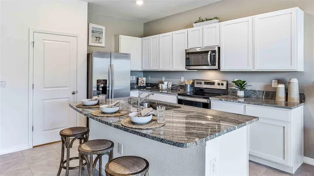 a kitchen with a sink a stove and chairs with kitchen island