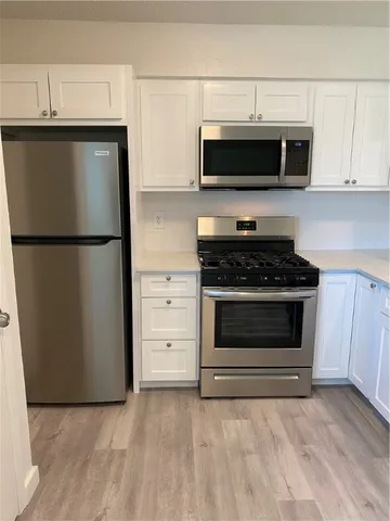a kitchen with stainless steel appliances white cabinets white stove a microwave and a refrigerator