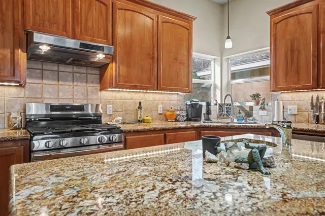 a kitchen with stainless steel appliances granite countertop a stove a sink and a microwave