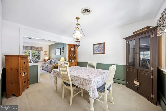 a open kitchen with stainless steel appliances granite countertop a stove top oven a refrigerator a dining table and chairs with wooden floor