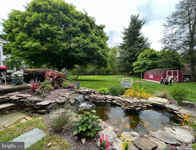 a view of a garden with flowers and large trees