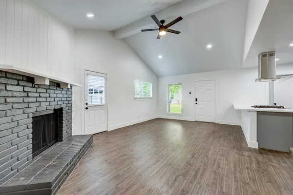 an empty room with windows fireplace and wooden floor