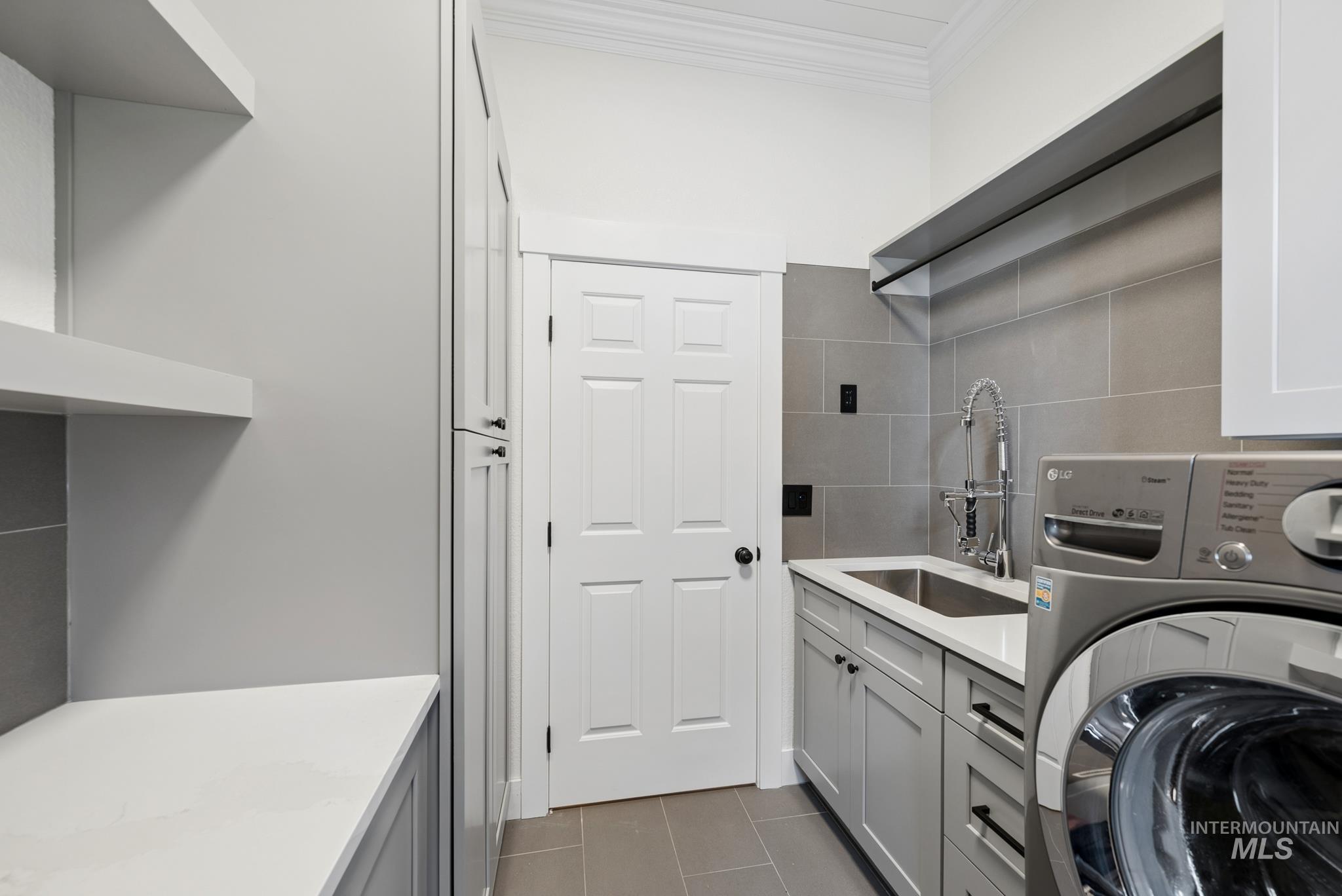 2050 Artesian Road Eagle, ID 83616 - Photo 38 of 49 Dedicated laundry room featuring light gray cabinetry with black hardware, a stainless steel utility sink with a commercial-style faucet, a white countertop, and light gray tile flooring