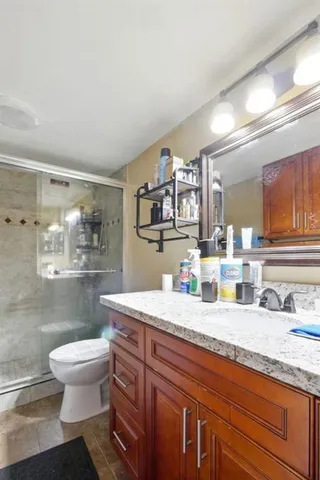 a bathroom with a granite countertop toilet sink and mirror