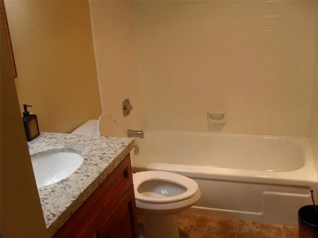 a bathroom with a granite countertop sink and a toilet