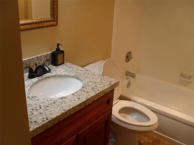 a bathroom with a granite countertop toilet sink and mirror