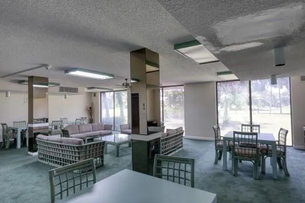 a room with lots of tables a large window and chairs