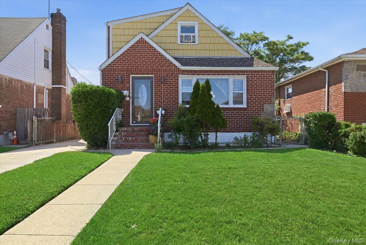 79 Wellington Road Elmont, NY 11003 - Photo 1 of 33 Brick and shingle exterior featuring a prominent front lawn, concrete pathway, and a paved driveway
