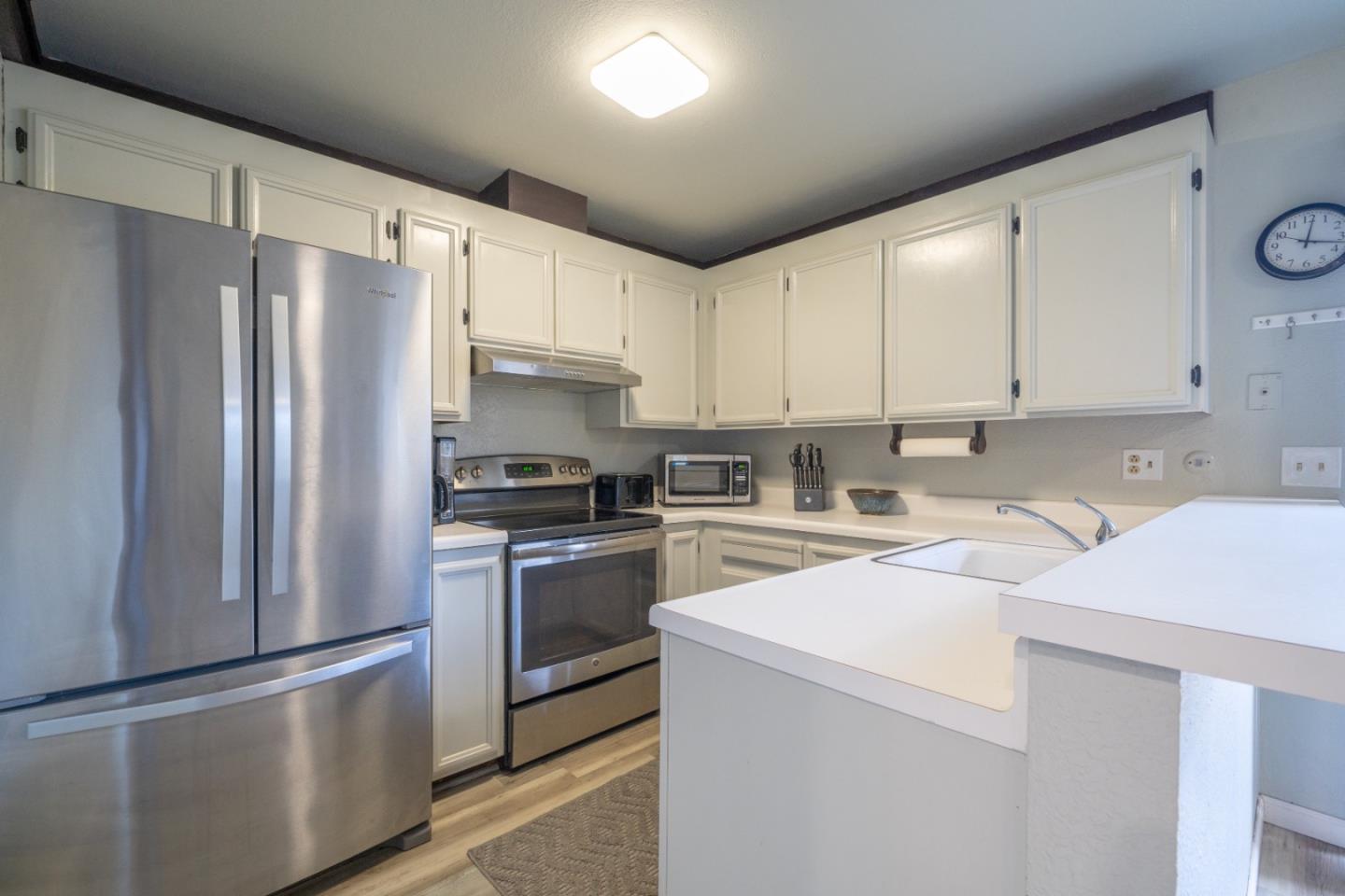 1267 Rosita Road Pacifica, CA 94044 - Photo 8 of 24 a kitchen with stainless steel appliances granite countertop a refrigerator sink stove and white cabinets