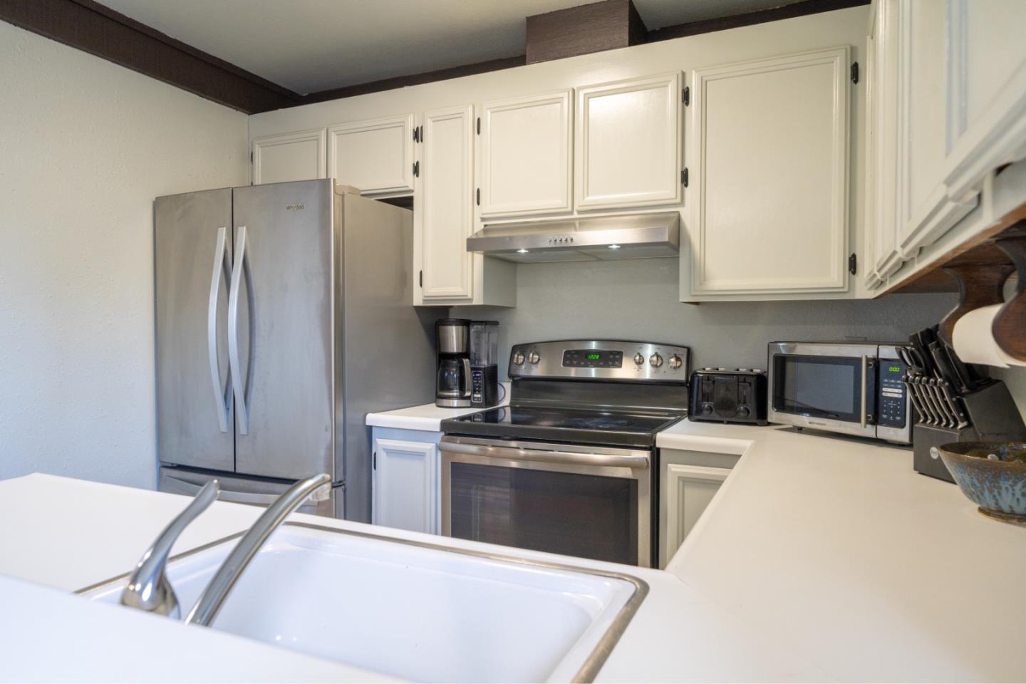 1267 Rosita Road Pacifica, CA 94044 - Photo 10 of 24 a kitchen with stainless steel appliances granite countertop a stove a refrigerator and a white cabinets