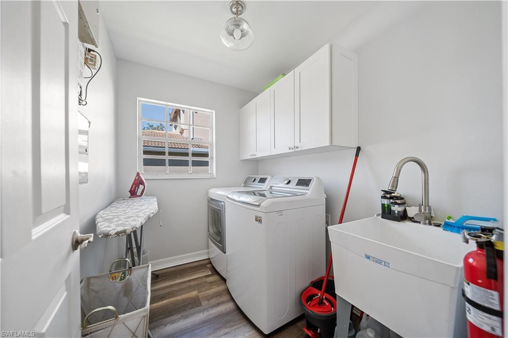 1638 Triangle Palm Terrace Naples, FL 34119 - Photo 16 of 21 Laundry room featuring washing machine and dryer, cabinet space, and wood finished floors