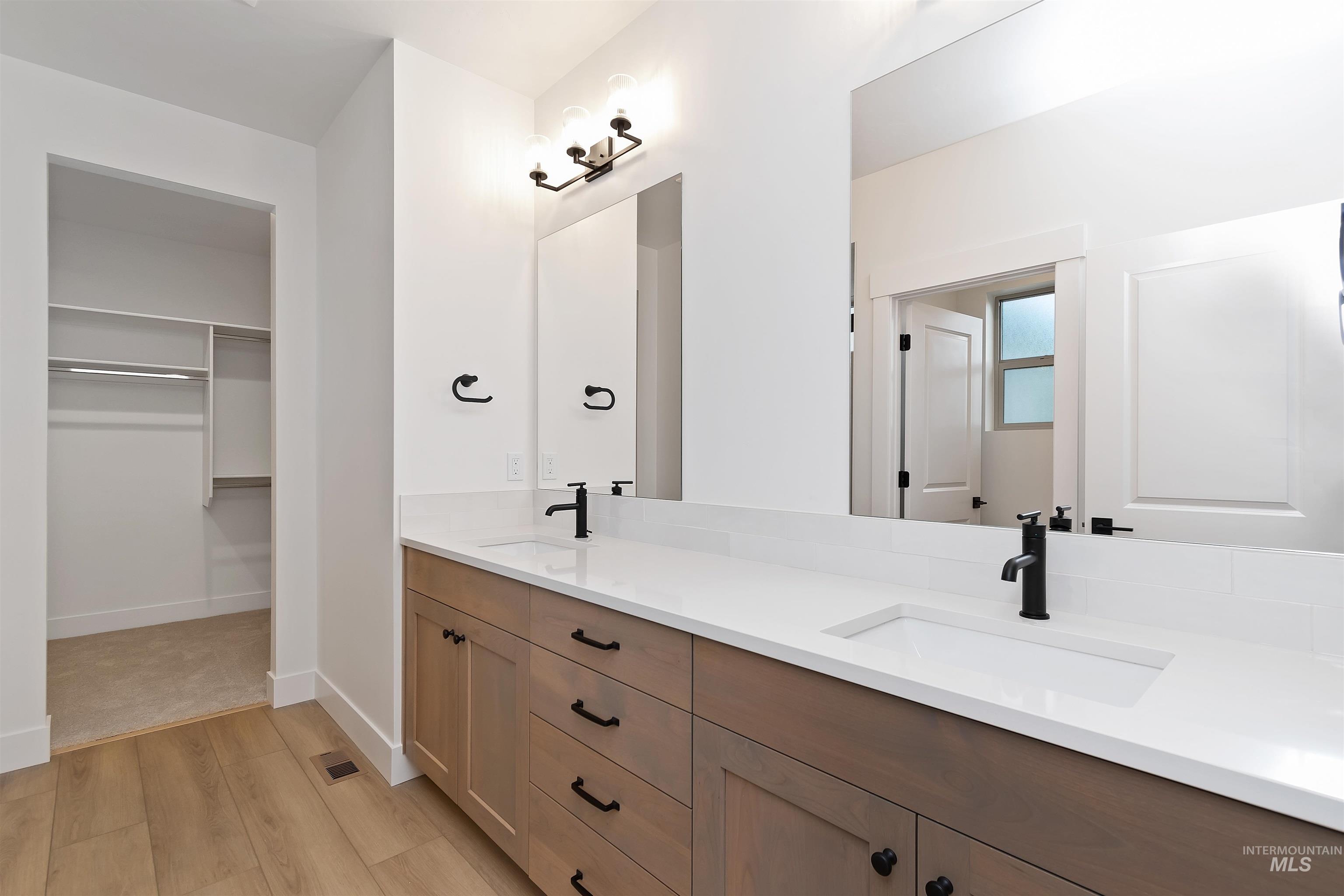 4302 Tropic Way Caldwell, ID 83607 - Photo 23 of 32 Bathroom featuring double vanity, light wood-style flooring, and a spacious closet