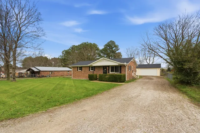 a view of a house with a big yard plants and large trees